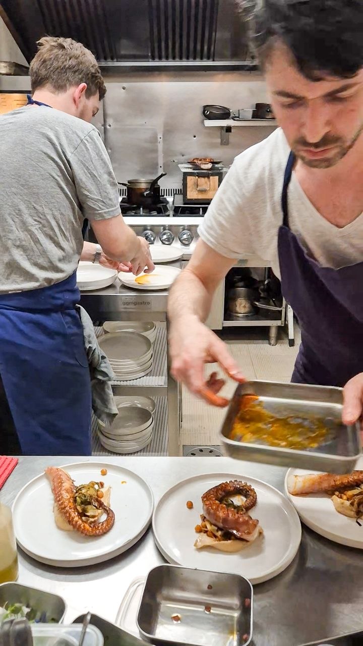 L'équipe en cuisine dresse une assiette de poulpe pendant le service à Alluma