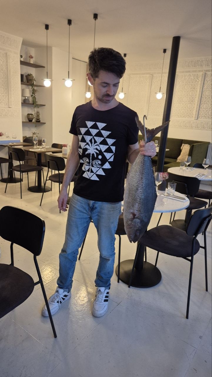 Un cuisinier d'Alluma tient un poisson entier dans la salle du restaurant